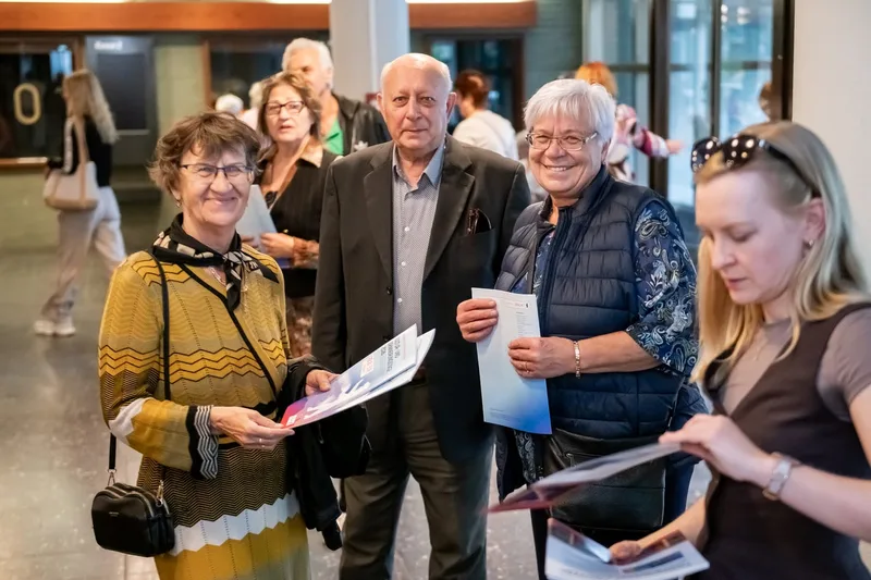 Besucherinnen und Besucher lesen Programmhefte im Foyer