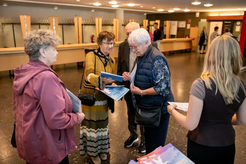 Gäste halten Programmhefte und unterhalten sich im Foyer