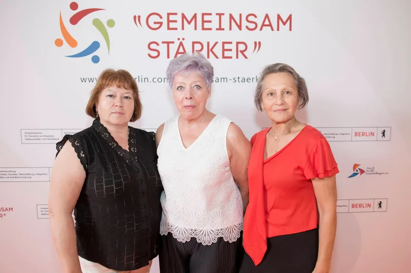 Drei Gäste vor der Fotowand mit „GEMEINSAM STÄRKER“