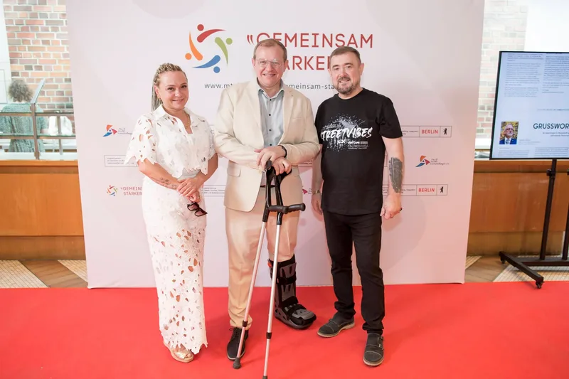 Drei Gäste auf rotem Teppich, einer mit Gehstock
