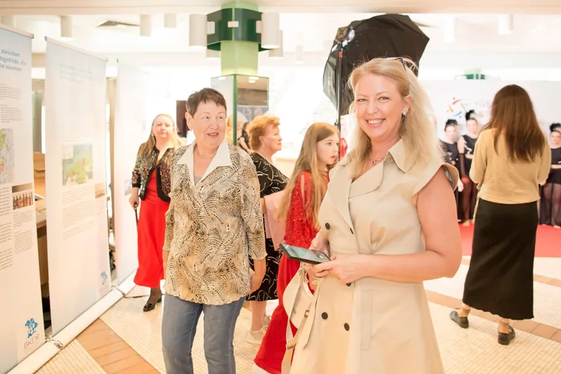 Besucherin in Creme-Kleid betrachtet Ausstellungsstände