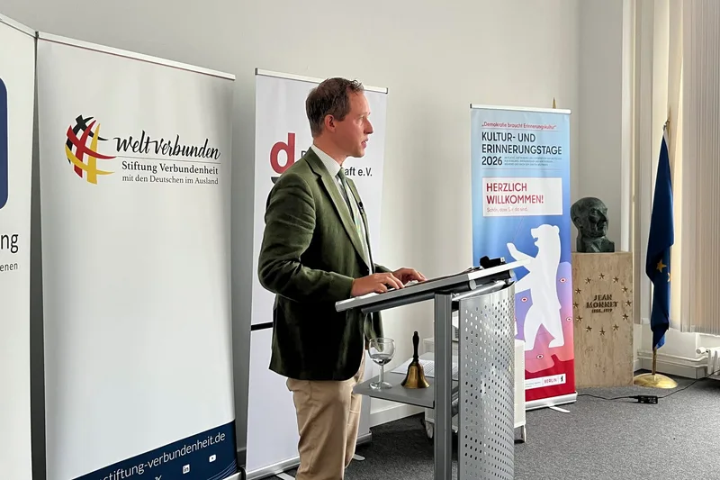 Ein Redner in grünem Jackett spricht vor dem Publikum