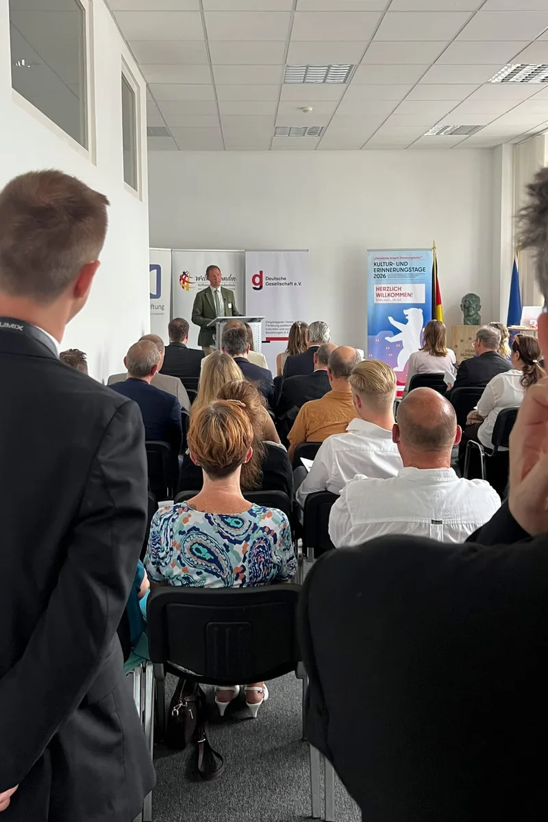 Publikum sitzt in Reihen und hört dem Redner zu